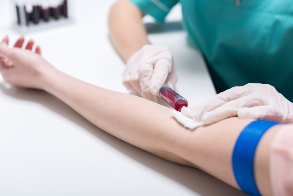 Медсестра берет образец крови со шприцем